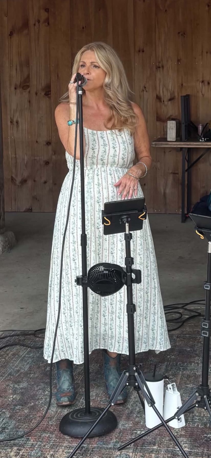 Tracie singing into a microphone on stage